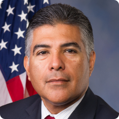 Congressional Representative Tony Cárdenas, wearing a blue suit, red tie...