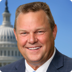 Senator Jon Tester, with Capitol in background. Official portrait.